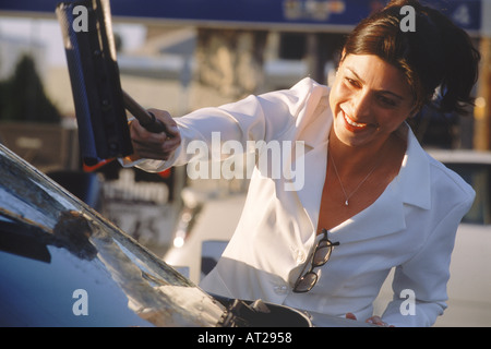 Frau im Business-Anzug, die Reinigung der Windschutzscheibe mit Griff wischen an SB-Tankstelle in USA Stockfoto