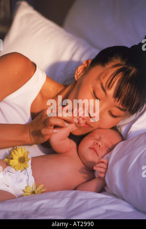 Asiatische Mutter mit Neugeborenen im Schlafzimmer Morgenlicht Stockfoto