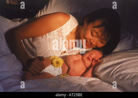 Asiatische Mutter mit ihrem Neugeborenen Baby im Schlafzimmer Morgenlicht Stockfoto