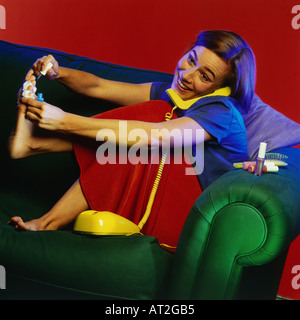 Eine Frau ihre Fußnägel Lackieren und sprechen am Telefon Stockfoto