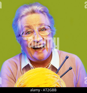 Eine ältere Frau hält eine eine Kugel aus Wolle und einige Stricknadeln Stockfoto