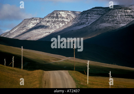 Eine unbefestigte Straße in Island s Vesterland Bezirk mit Schnee bedeckt Hallmundarhraun Berge im Hintergrund Stockfoto