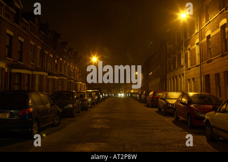 Auto nähert sich in der Mitte von einer schmalen dunklen nächtlichen Straße in Belfast Stockfoto