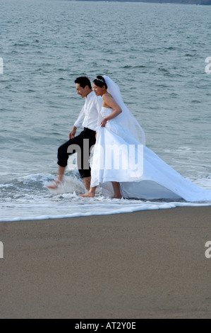 Braut & Bräutigam stehen Wandern In Wellen des Ozeans Stockfoto