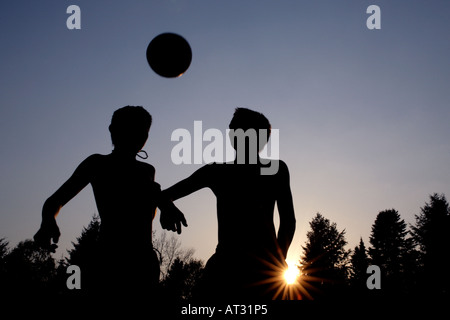 zwei jungen einen Ball vor der untergehenden Sonne in Richtung Stockfoto