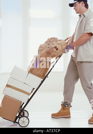 Eine Lieferung Mann schob einen Trolley mit Parzellen drauf Stockfoto