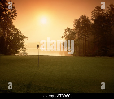 Sonne an einem nebligen Morgen über einen Golf Grün in North Carolina mit einem See im Hintergrund Stockfoto