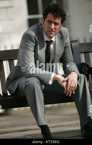 Ein Mann sitzt auf einer Bank denken Stockfoto