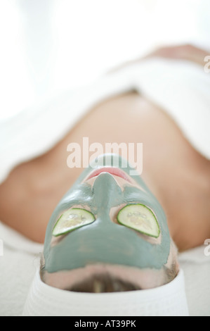 Eine Frau in eine Gesichtsmaske mit Gurke über die Augen entspannen Stockfoto