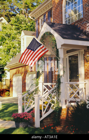 Nahaufnahme von der Vorderseite des roten Backsteinhaus mit blauen Fensterläden White trim und eine amerikanische Flagge, die in der Nähe der Eingangstür hängen Stockfoto