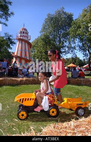 EINE MUTTER HILFT IHR KIND SPIELEN AUF EIN SPIELZEUG MULDENKIPPER AN UNSCHULDIGEN DORFFEST IM REGENTS PARK LONDON 2007 Stockfoto