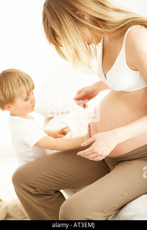 Ein kleiner Junge seine Mutter schwanger Bauch zu berühren Stockfoto