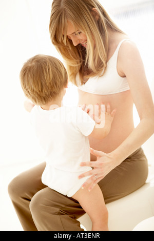 Ein kleiner Junge mit den Händen auf seine Mutter schwanger Bauch Stockfoto