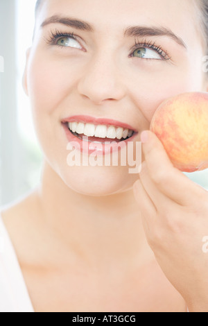 Junge Frau mit einem Pfirsich, Lächeln Stockfoto