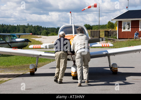 Zwei Männer drängen ein kleines Flugzeug auf der Startbahn Stockfoto