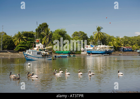 Costa Rica Quepos Pelikane in der Nähe von Sport Angelboote/Fischerboote vertäut an der Mündung des Flusses bei Ebbe Stockfoto