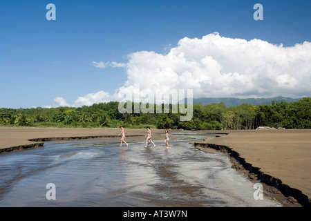 Costa Rica Uvita Parque Nacional Marino Bellena Familie Überquerung kleiner Bach am einsamen Strand Stockfoto