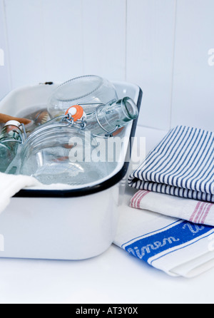 Leinen Geschirrtücher und ein Emaille Schüssel gefüllt mit Vintage-Flaschen waschen Stockfoto