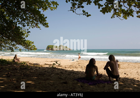 Costa Rica Karibik Küste Puerto Viejo de Talamanca Cocles Sonnenanbeter und Surfer auf weichen Sandstrand im Schatten sitzen Stockfoto