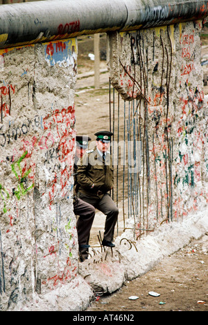 Der Fall der Berliner Mauer 1989. Ostdeutschen Wachen sehen den Westen vorbei durch ein Loch in der Wand. Stockfoto
