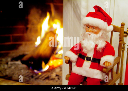 Santa Clause Mannequin, sitzt auf einem Schaukelstuhl neben dem Kamin Stockfoto