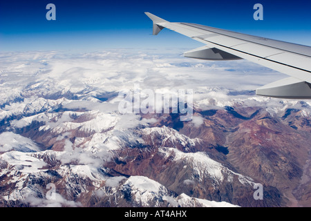 Luftbild von der Cordillera de Los Andes Mountains zwischen den Wolken zwischen Chile und Argentinien. Die Tragfläche eines Flugzeugs gesehen. Stockfoto