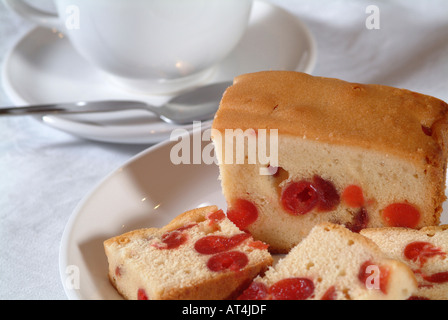 Kirsch Kuchen in Scheiben geschnitten auf einem weißen Teller mit Löffel Tasse und Untertasse auf weiße Tischdecke Stockfoto