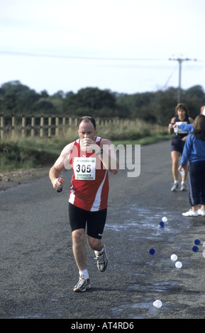 Läufer Trinkwasser während Kenilworth Halbmarathon Rennen, Warwickshire, England, UK Stockfoto