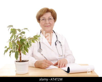 Porträt der Familie Oberärztin mit Stethoskop sitzt hinter einem Schreibtisch mit Notepad und eingemachten grünen Baum auf weißem Hintergrund Stockfoto