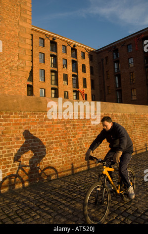 Mann, Radfahren auf dem Kai Weg am Albert Dock Liverpool bei Sonnenuntergang Stockfoto