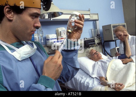 Frau im Krankenhaus mit ihrem Blutdruck genommen, während der Arzt eine Spritze füllt sich mit Medizin Stockfoto