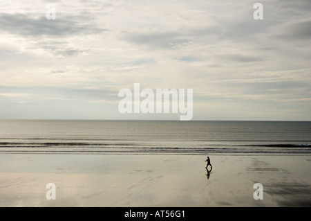 einzelne Person allein zu Fuß am einsamen Strand im Herbst oder Winter bei Ebbe, Borth Ceredigion Wales UK Stockfoto