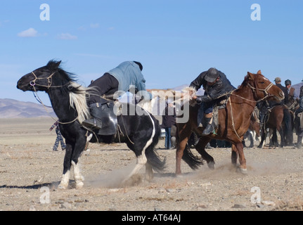 Zwei kasachische Fahrer kämpfen um die Kontrolle einer toten Ziege in einem Spiel von Kokpar oder Bushkashi am jährlichen Adler-Jagd-Festival Stockfoto