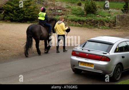 Pony und Reiter tragen eine Bitte Pass breit und langsam Jacke auf Feldweg mit Übergabe Auto England UK Stockfoto