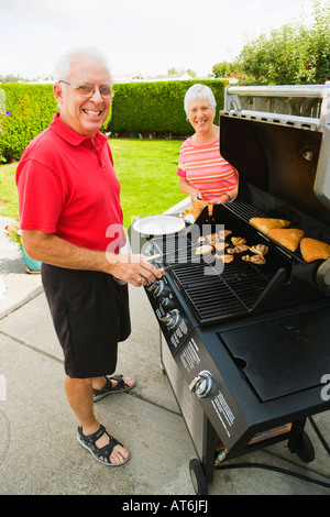 Porträt von ein älteres paar kochen bei einem Barbecue auf der Terrasse Stockfoto