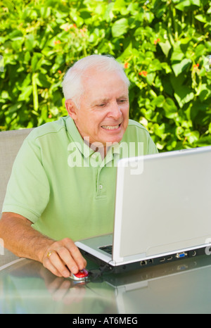 Reifer Mann verzog das Gesicht und ballte seine Zähne während der Arbeit an seinem Laptopcomputer Stockfoto