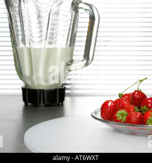 Erdbeeren auf Teller vor Mixer, Nahaufnahme Stockfoto