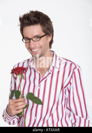 Junger Mann hält eine Rose, Porträt Stockfoto
