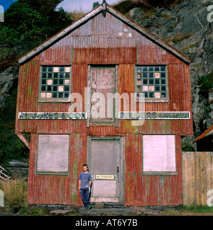 Junge, der vor dem baufälligen, redundanten Wellblechlager R L Jones Sons Builders Blaenauffestiniog North Wales Großbritannien KATHY DEWITT STEHT Stockfoto