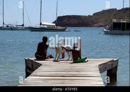 Junge Mann und Hund an einem Anlegesteg in English Harbour, Antigua, West Indies. Stockfoto