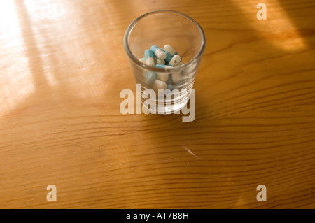 Prozac-Kapseln in einem Schnapsglas auf einer Holzmaserung Oberfläche. Stockfoto