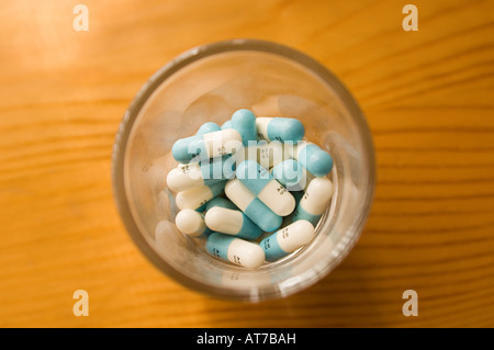 Prozac-Kapseln in einem Schnapsglas auf einer Holzmaserung Oberfläche. Stockfoto