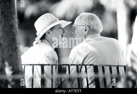 Ein älteres Paar eng auf einer Parkbank im Gespräch Stockfoto