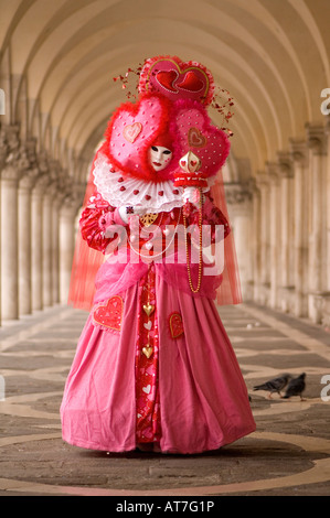 Karneval in Venedig Dame im rosa Kostüm stehen zentral in einer Allee von Bögen und Marmorsäulen St. Markusplatz Venedig MASKE FESTIVAL Stockfoto