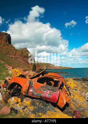 Ein Rost Auto liegt auf Klippe Felsen mit Blick auf die Küste hinter sich Stockfoto