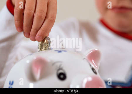 Kind, Geld in Sparschwein Stockfoto