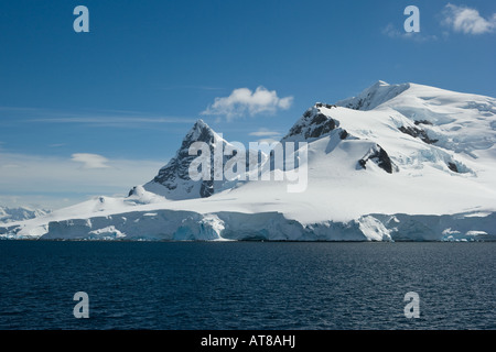 Kleine Wolke vor einem strahlend blauen Himmel auf dem Gipfel des einen überdachten Schneeberg in der antarktischen Halbinsel bilden Stockfoto
