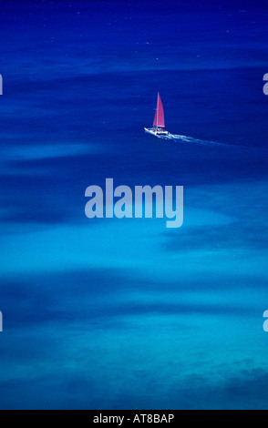 Glänzendes blaue Wasser umgibt vollständig weißen Katamaran kreuzen vor der Küste von Waikiki mit wogenden Fuschia rosa Stockfoto