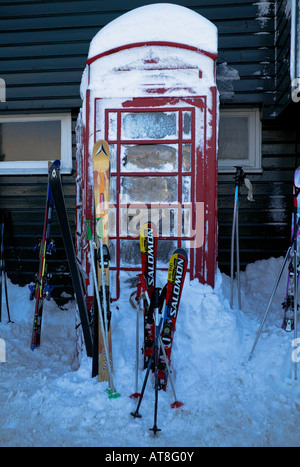 Rote Telefonzelle durch Schnee und Ski umgeben, Cairngorms National Park Glenshee Skigebiet Aberdeenshire und Perthshire Stockfoto