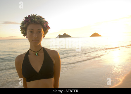 schöne junge Frau tragen Badeanzug und Haku Lei (floralen Kopfschmuck) steht am Ufer am Strand von Lanikai auf der Luv Stockfoto